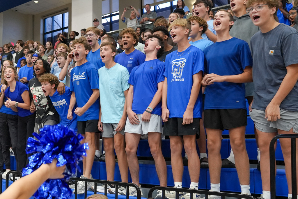 High school students shout while standing in bleachers during a pep rally.