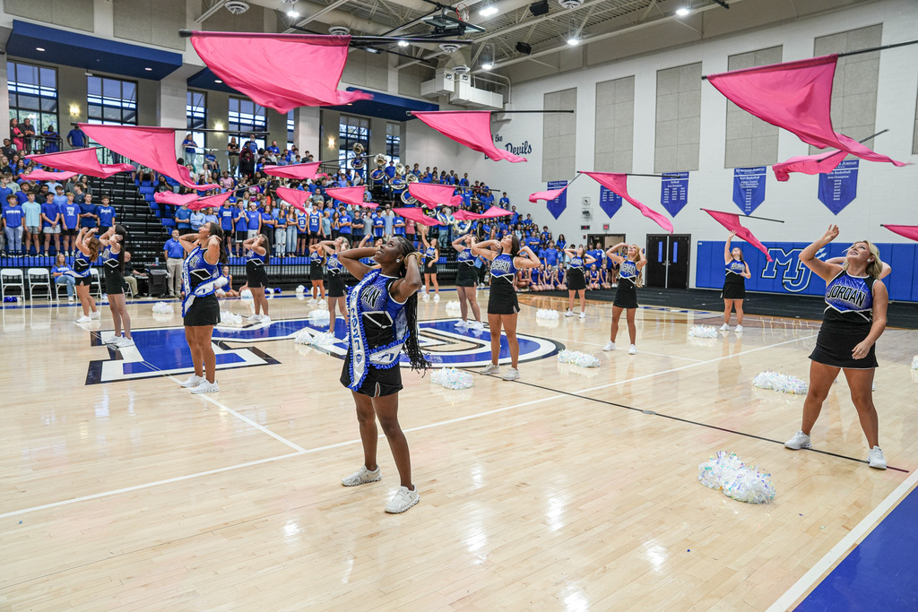 Color guard members throw flags in the air during a performance at a pep rally.