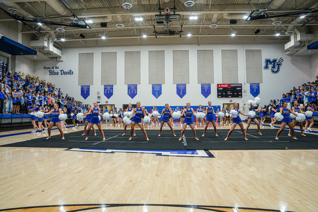 A dance team performs inside a school gym during a pep rally.
