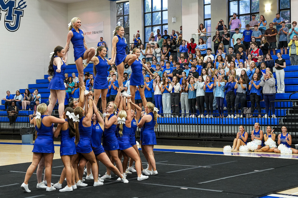Cheerleaders form a pyramid in a school gym during a pep rally.
