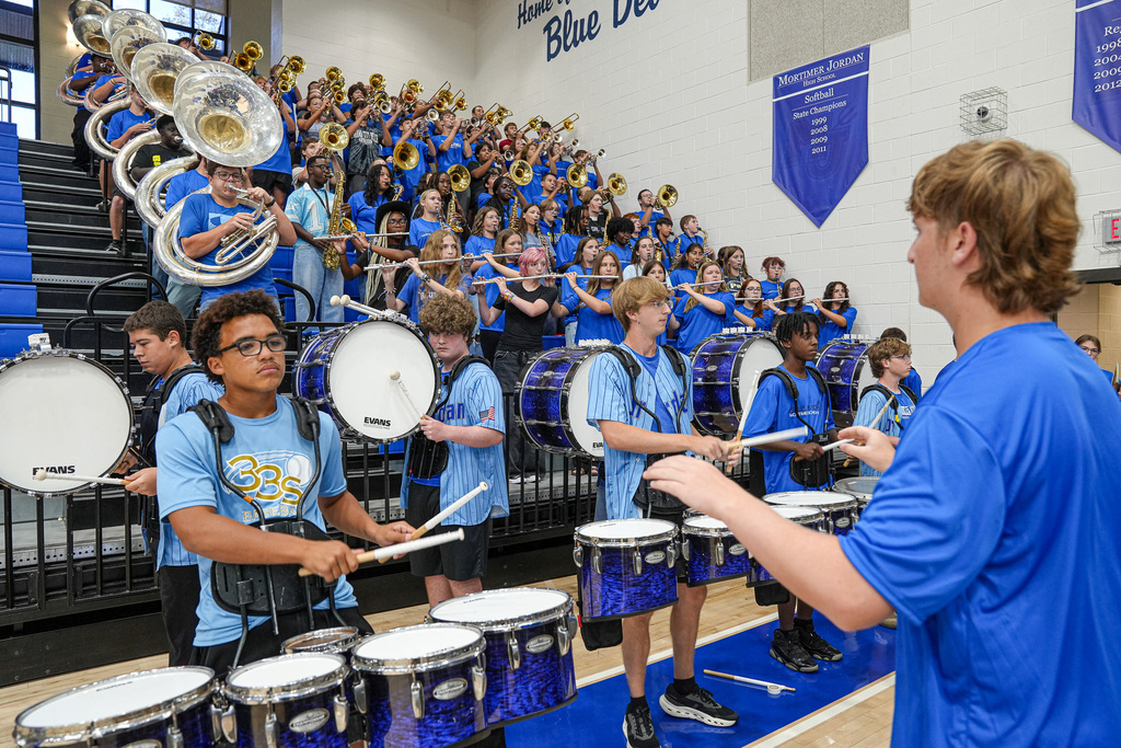 A marching band performs inside a school gym.