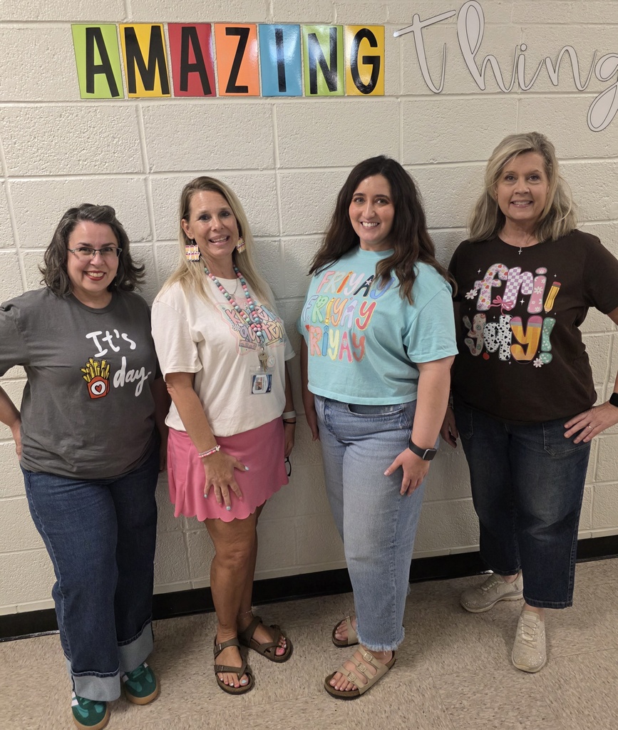 4 teachers standing in front of a wall with shirts that say "Fri-yay!"