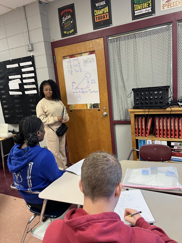 a student solves a math problem on a sheet of paper in front of their group