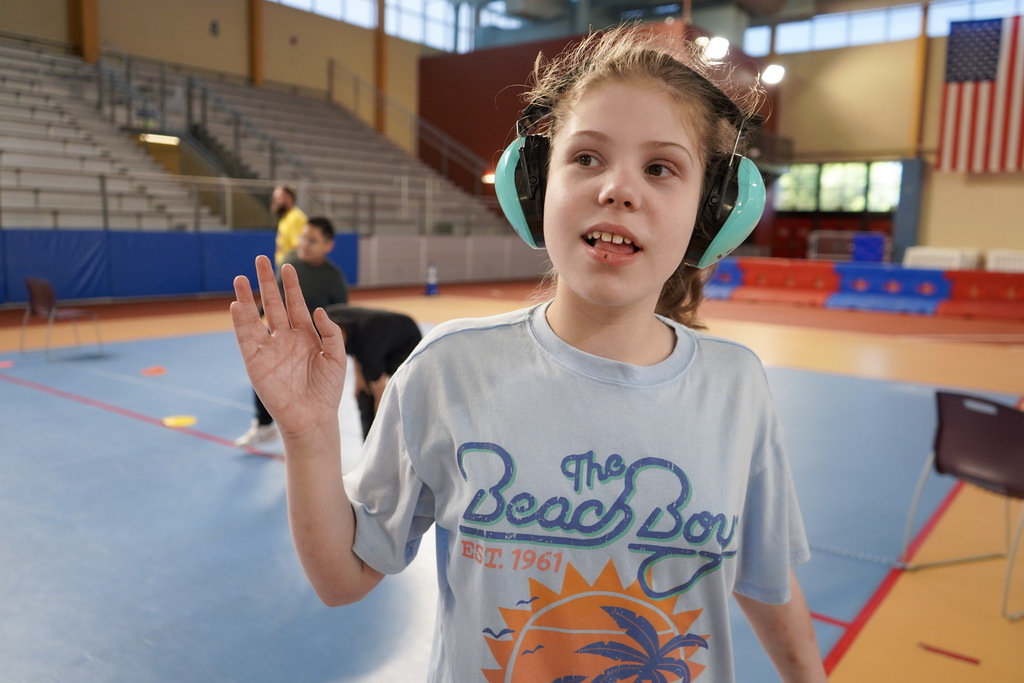 A student smiles while standing in a gymnasium.
