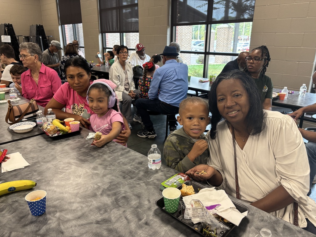 Grandparents and students smiling together during the school’s Grandparents Day Brunch. Families are gathered around tables enjoying breakfast, visiting, and celebrating time together on campus.