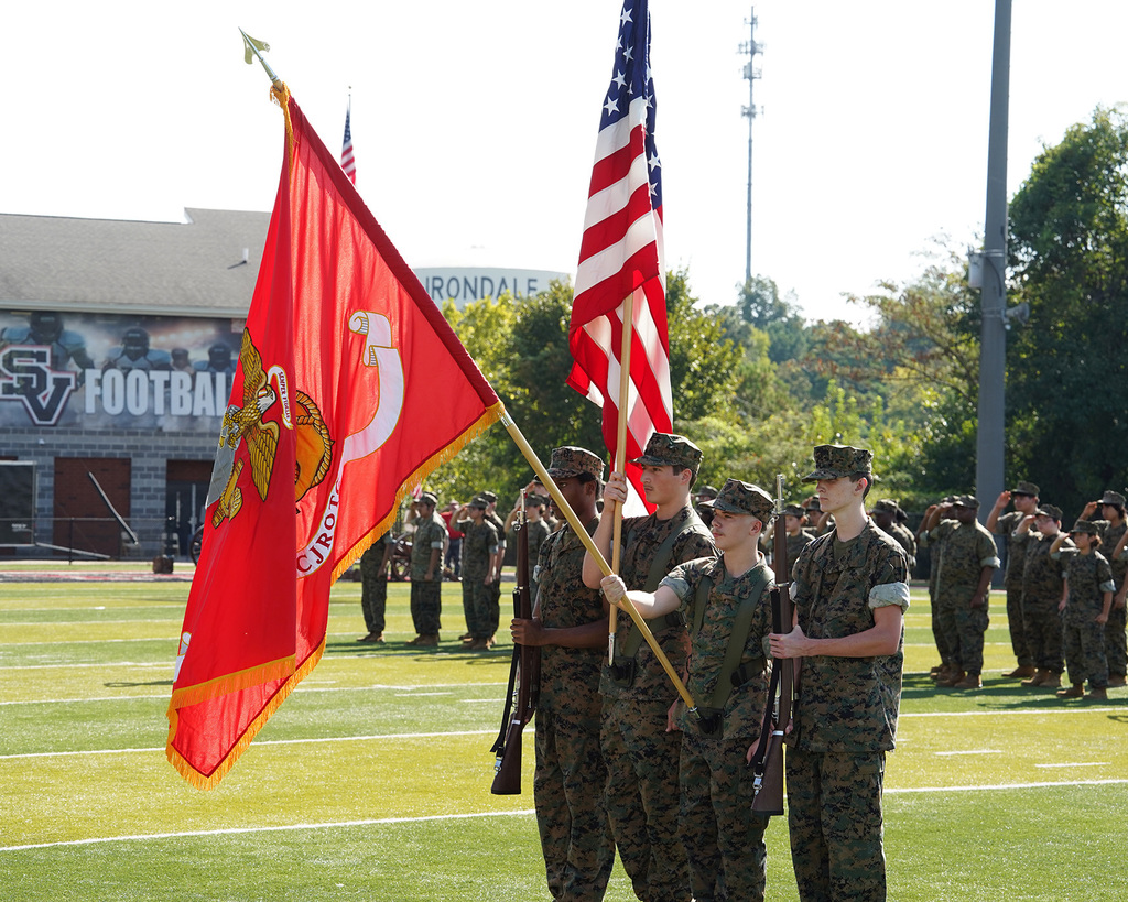 JROTC members present flags during a ceremony on a football field.