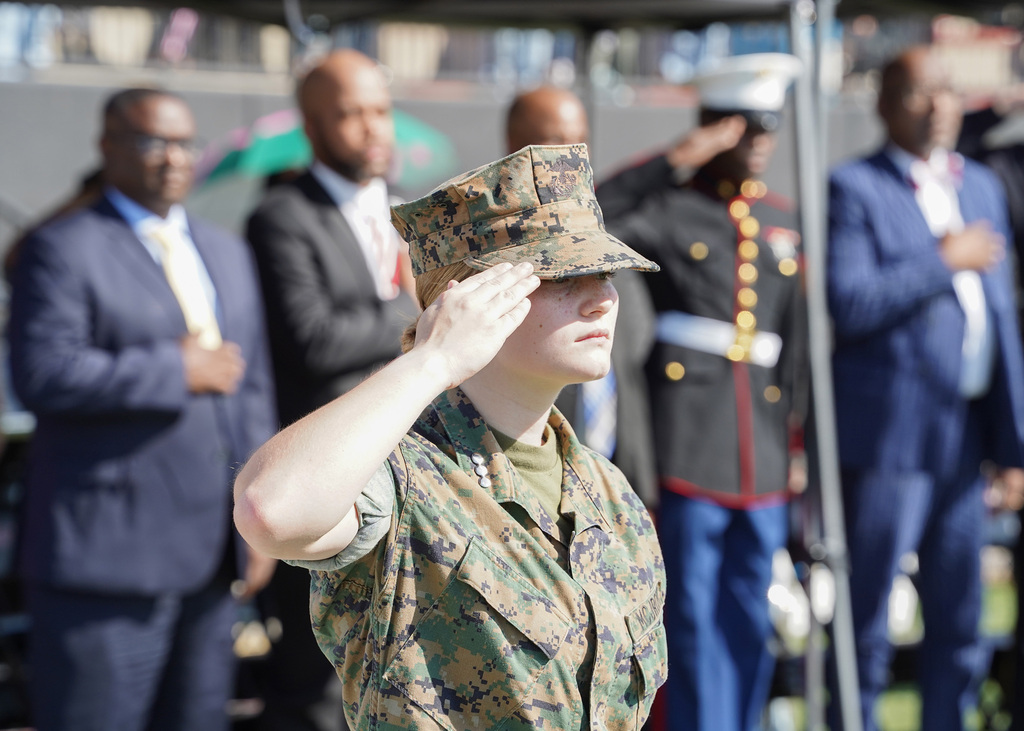 A student salutes while wearing a JROTC uniform outdoors.