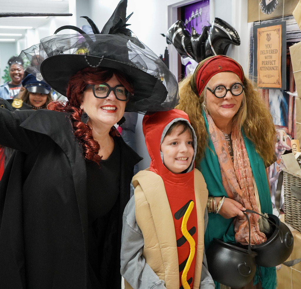 Adults and a child wearing Halloween costumes pose for a photo inside a building.