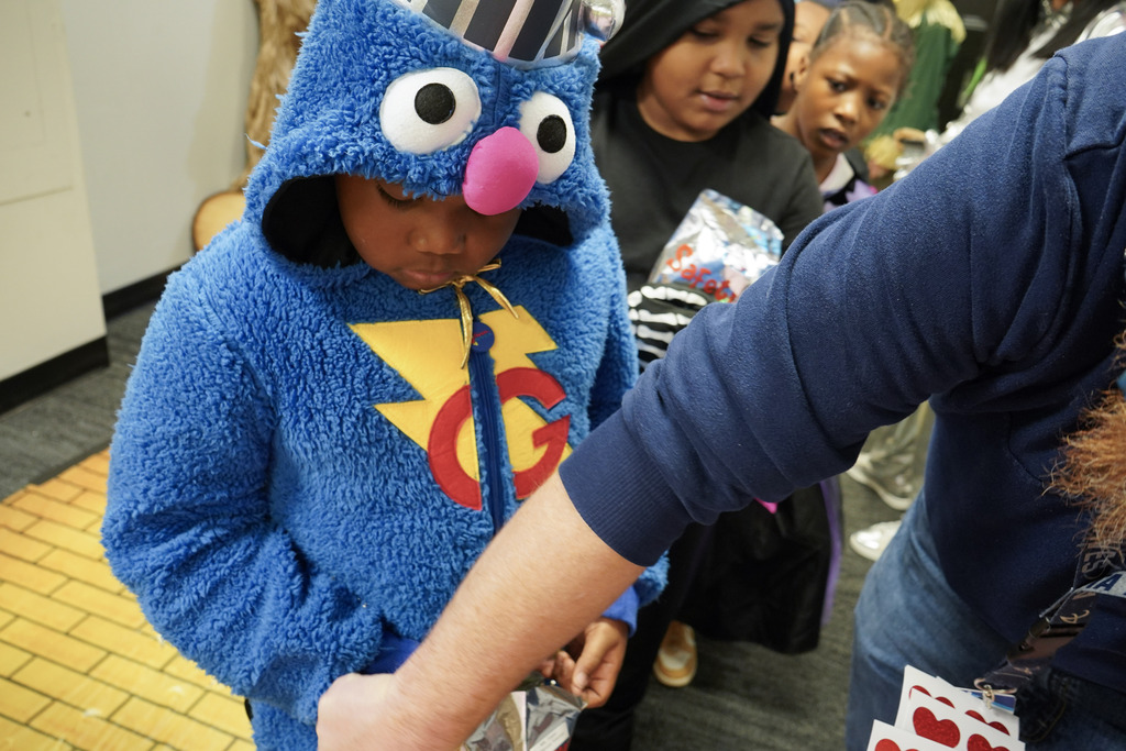A child wearing a costume trick-or-treats while standing inside a building.