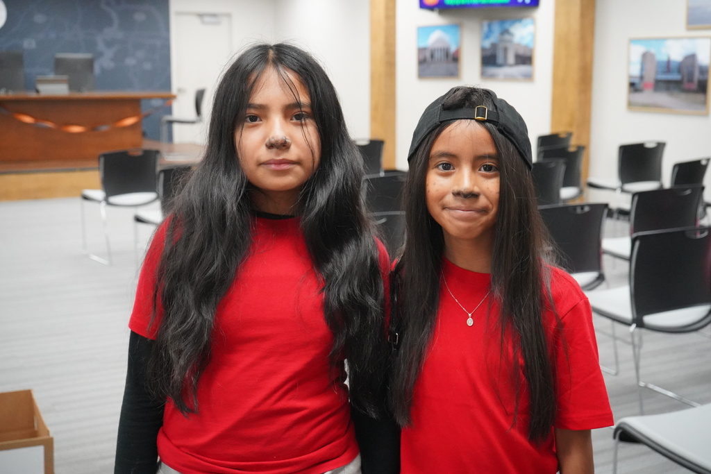 Students wearing Halloween costumes smile for a photo while standing in a room.