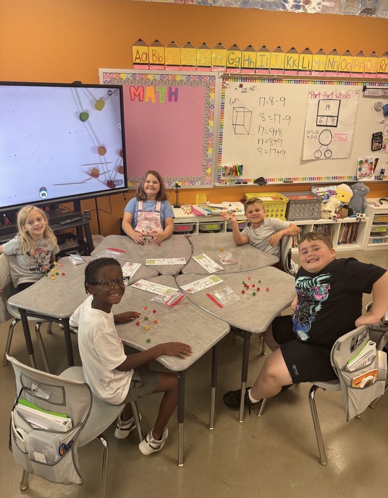5 students sitting at a desk group creating shapes using dot candy and tooth picks