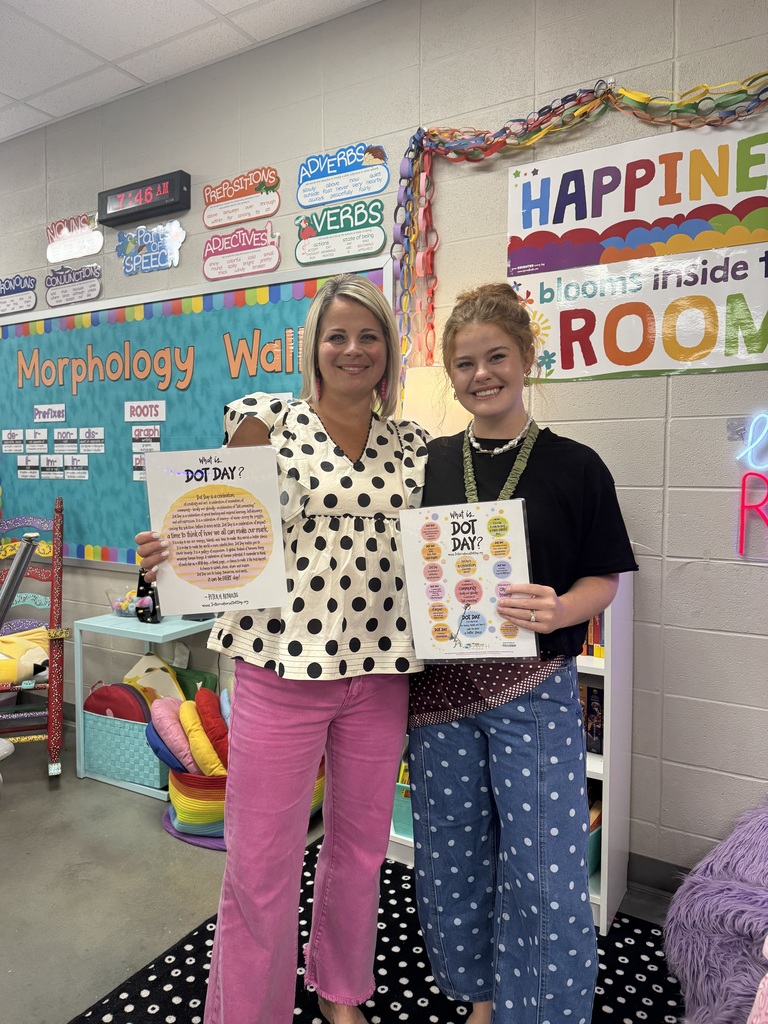 Two teachers holding dot day signs dressed in polkadot clothing.
