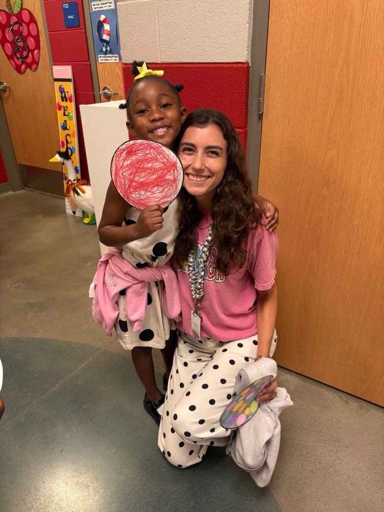 teacher and student posing with student dot art work in dot clothing