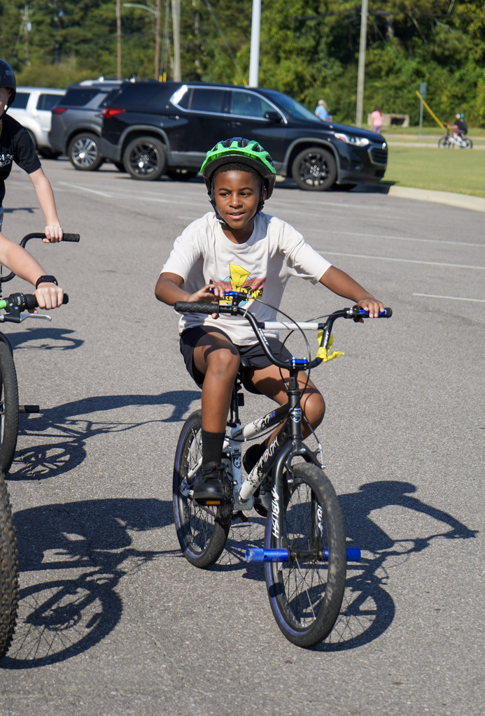 A child rides a bike through a parking lot.