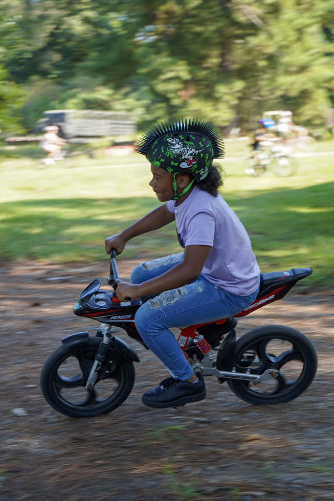A child rides a bike through a grassy area.