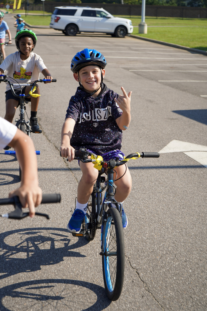 A child smiles while riding a bicycle outdoors.