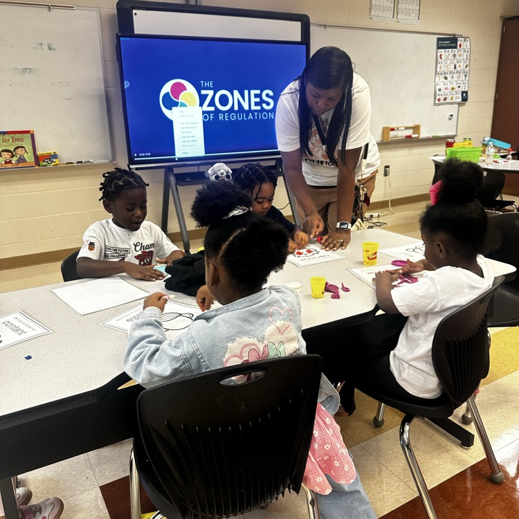 teacher helping students complete a class project about emotions