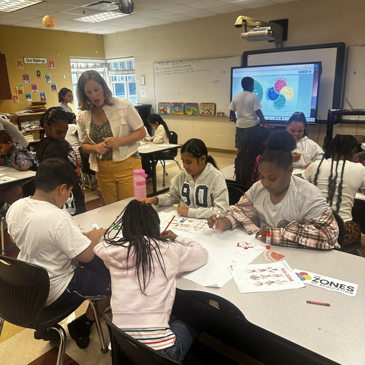 teacher helping students complete a class project about emotions