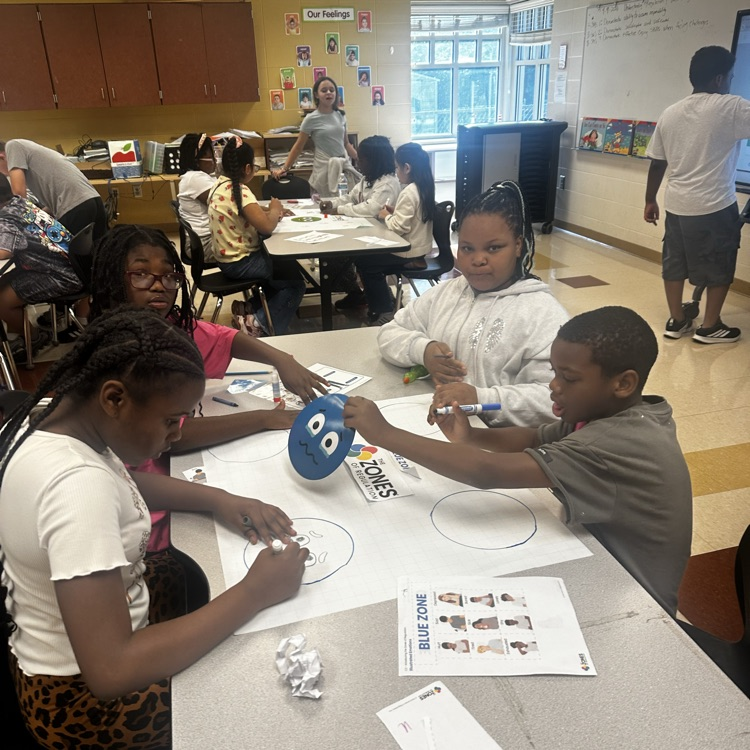 teacher helping students complete a class project about emotions