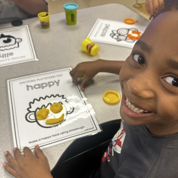 students smiling while holding their unfinished craft