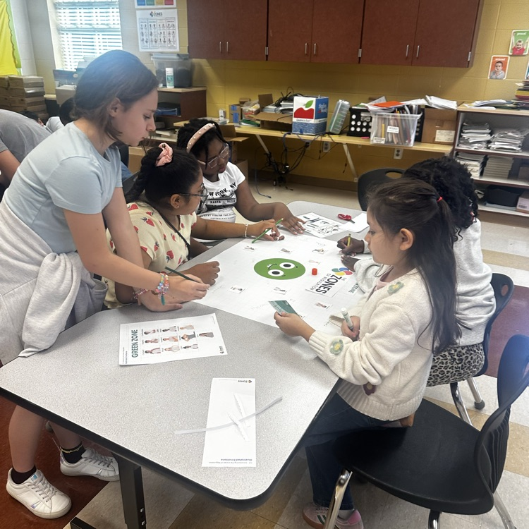 older kid helping students complete a class project about emotions