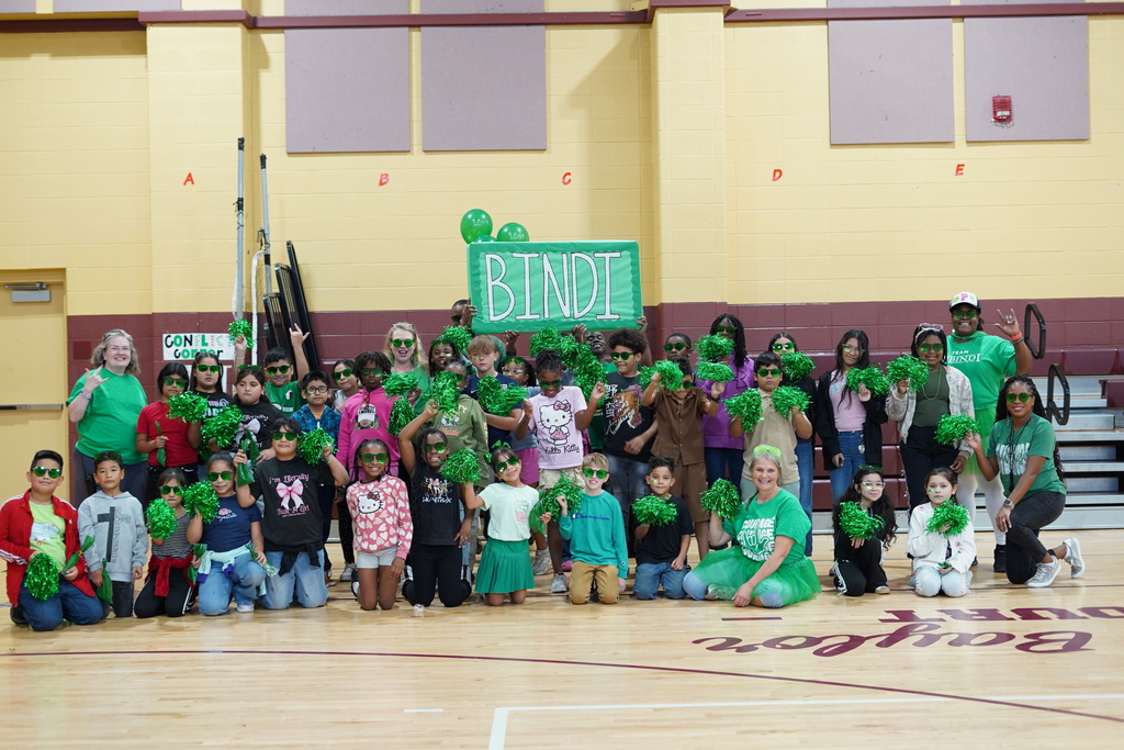 Students and teachers smile for a photo in a school gym.