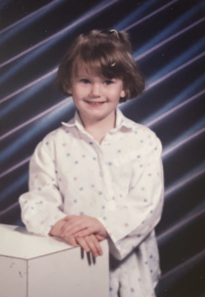 A childhood school portrait of a McCalla Elementary teacher or staff member, shared as part of a fun Picture Day guessing game for families.