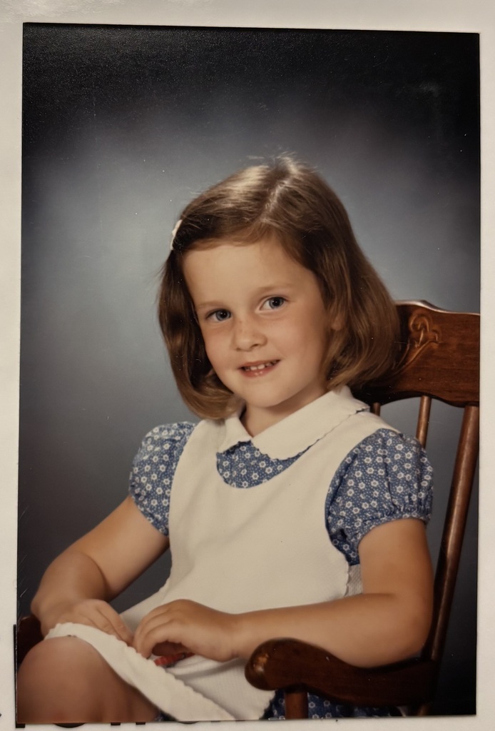 A childhood school portrait of a McCalla Elementary teacher or staff member, shared as part of a fun Picture Day guessing game for families.
