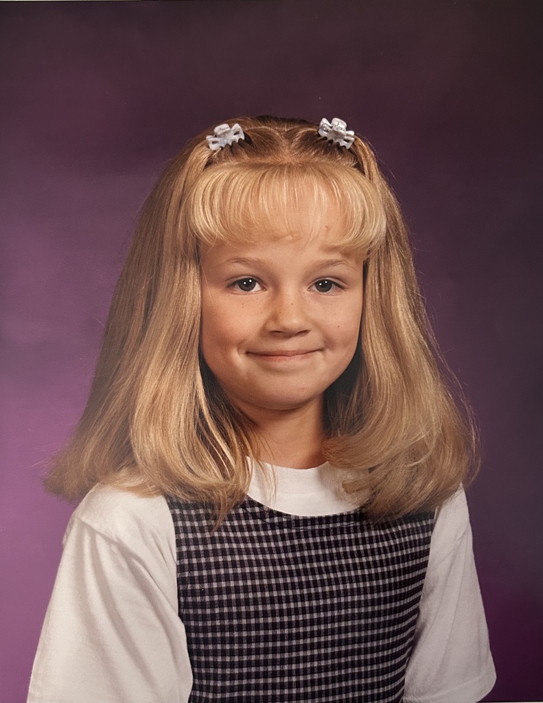 A childhood school portrait of a McCalla Elementary teacher or staff member, shared as part of a fun Picture Day guessing game for families.