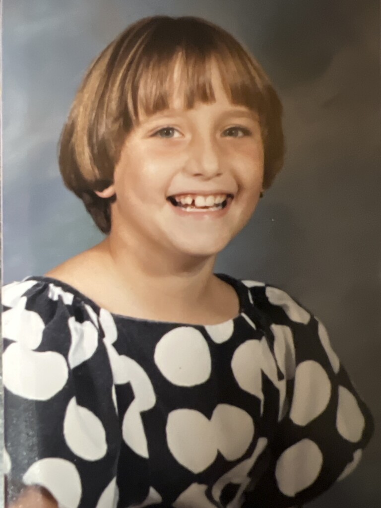 A childhood school portrait of a McCalla Elementary teacher or staff member, shared as part of a fun Picture Day guessing game for families.