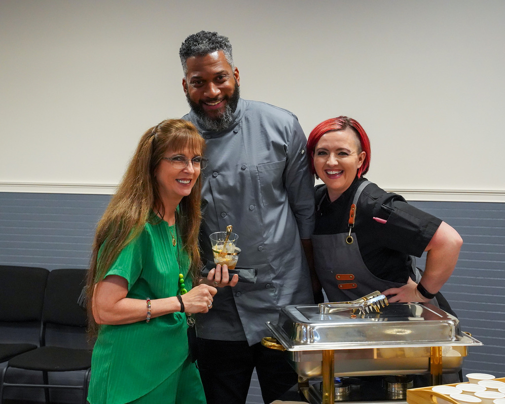 Three members of the Jefferson County schools career tech program smile for the camera during Bobby Jackson's retirement party.