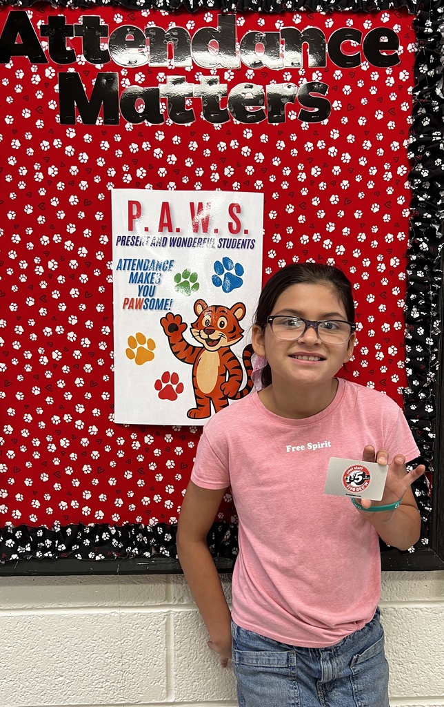 Picture of a student holding a gift card in front of a bulletin board