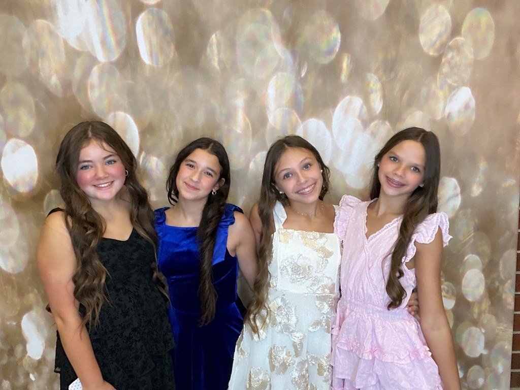 Students in front of a gold back drop at a homecoming dance