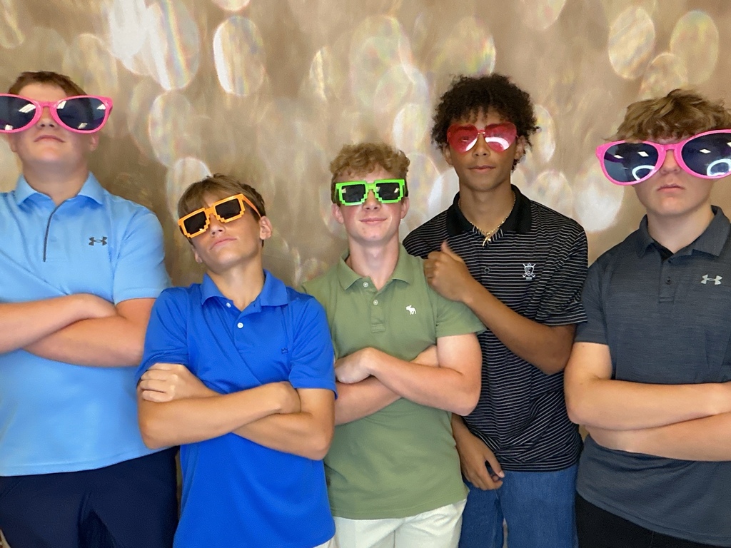 Students in front of a gold back drop at a homecoming dance