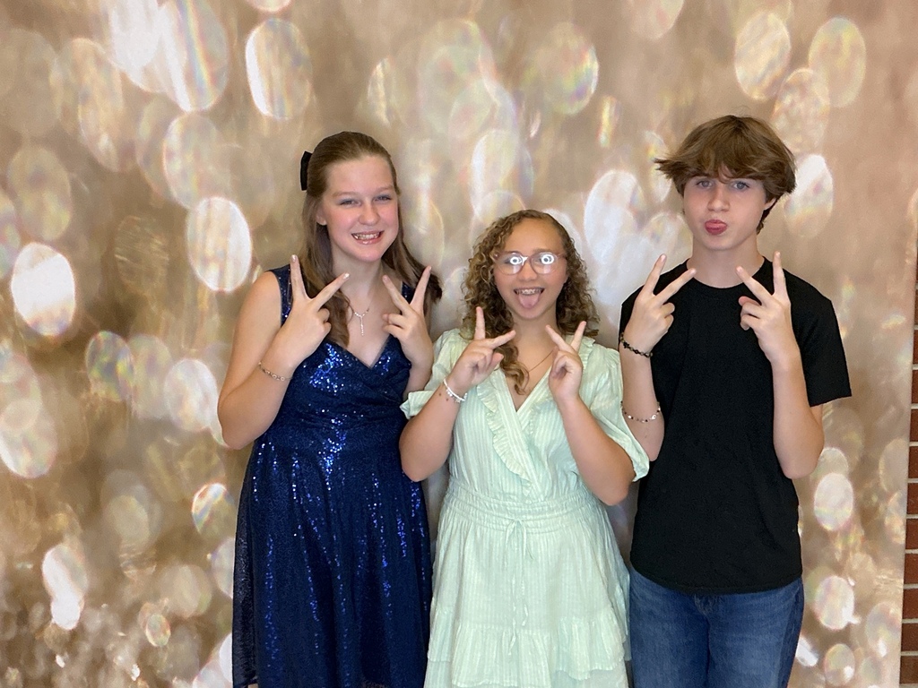 Students in front of a gold back drop at a homecoming dance