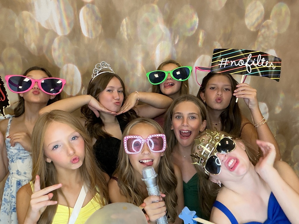 Students in front of a gold back drop at a homecoming dance