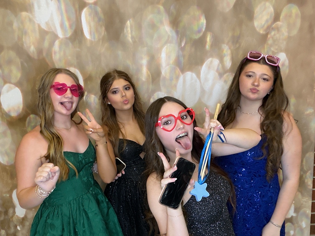 Students in front of a gold back drop at a homecoming dance