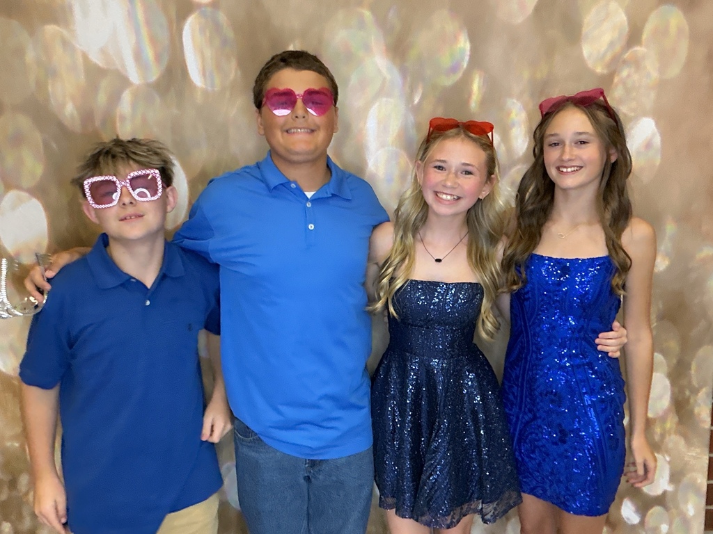 Students in front of a gold back drop at a homecoming dance