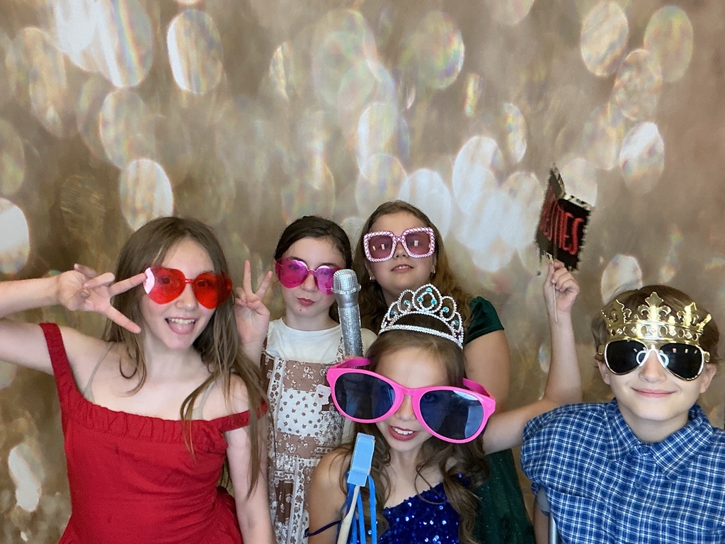 Students in front of a gold back drop at a homecoming dance