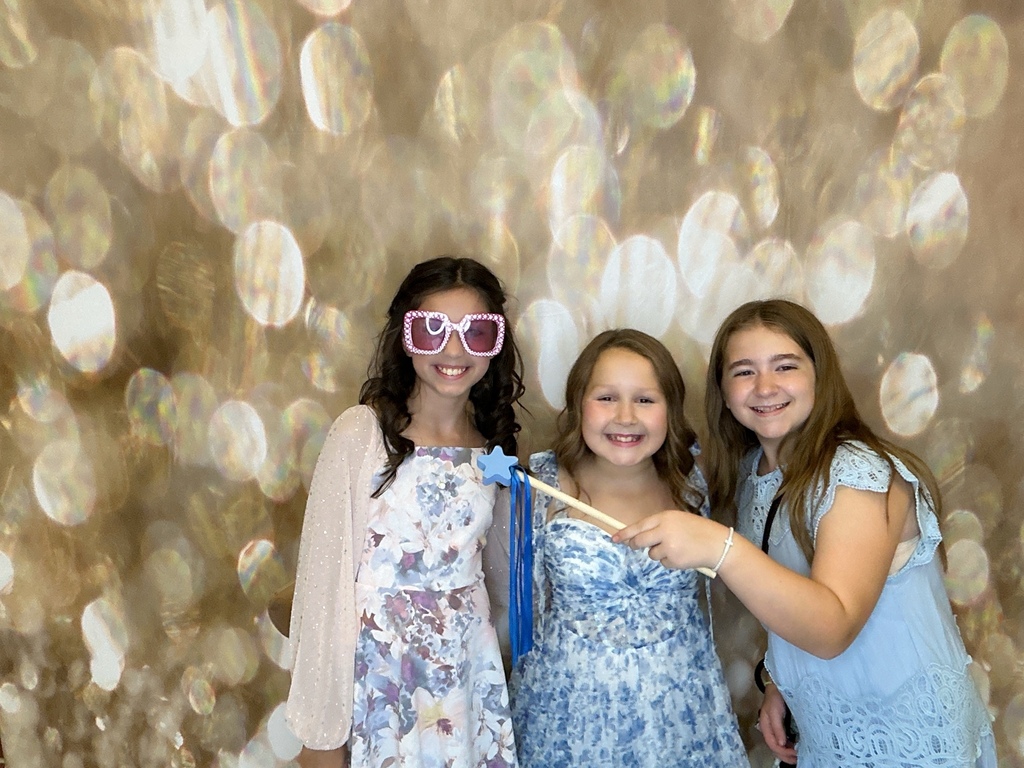 Students in front of a gold back drop at a homecoming dance