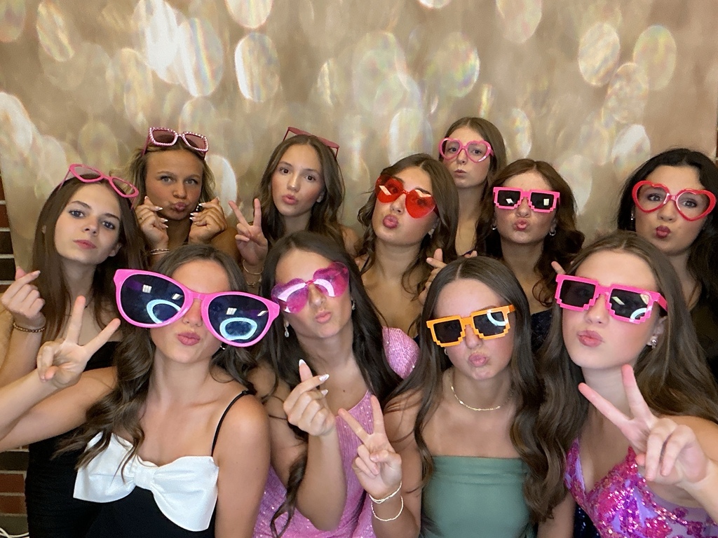 Students in front of a gold back drop at a homecoming dance