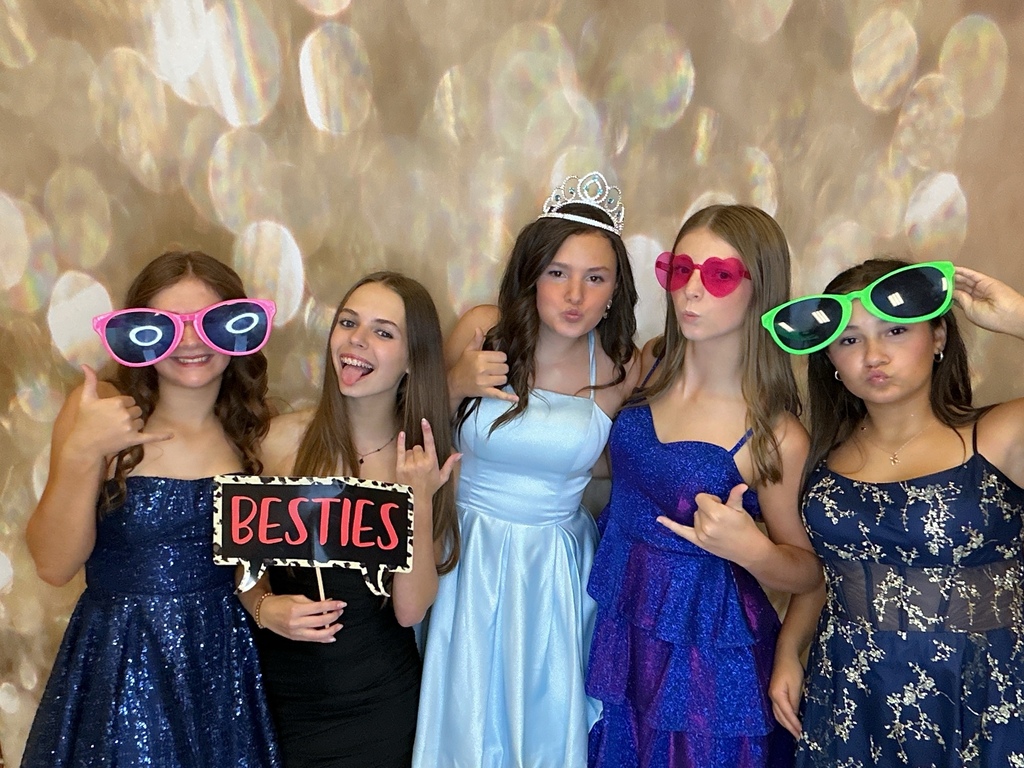 Students in front of a gold back drop at a homecoming dance