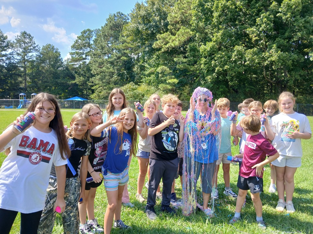 Students smiling for the camera with teacher all sprayed with silly string