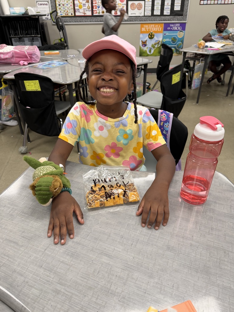 A student smiling with the bag of snack mix they made with their class