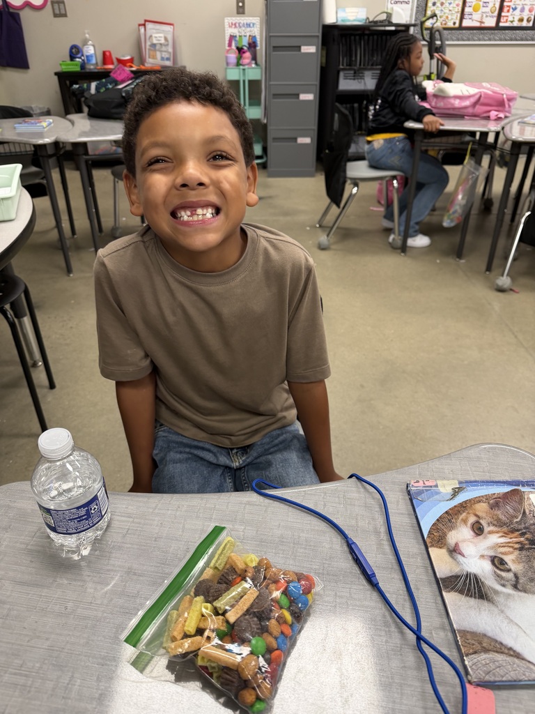 A student smiling with the bag of snack mix they made with their class