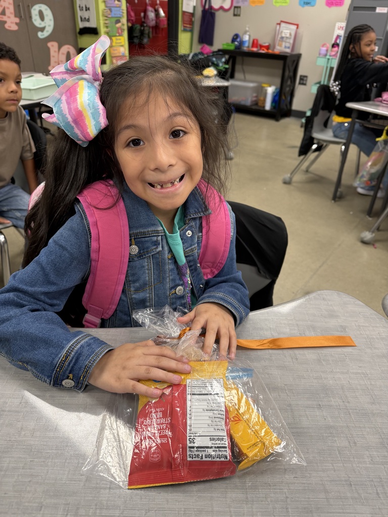 A student smiling with the bag of snack mix they made with their class