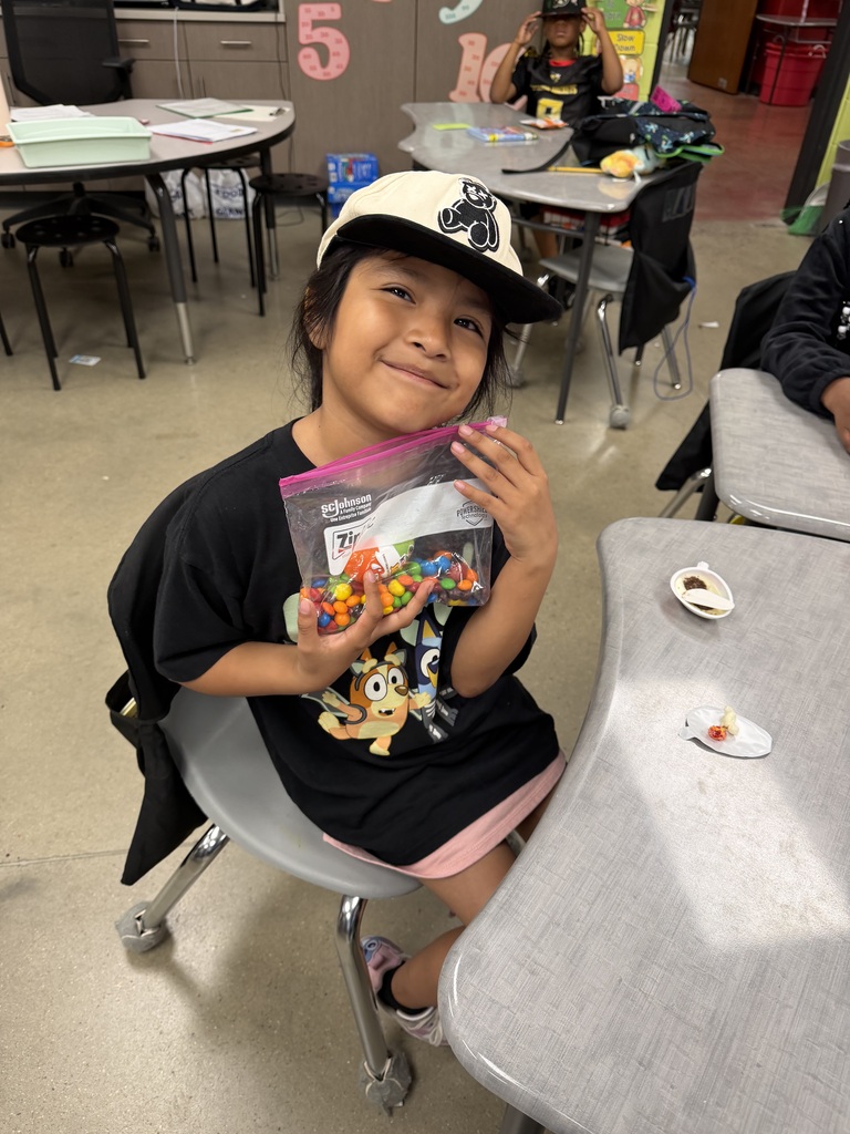A student smiling with the bag of snack mix they made with their class