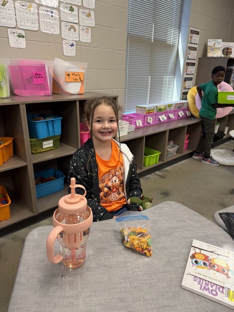 A student smiling with the bag of snack mix they made with their class