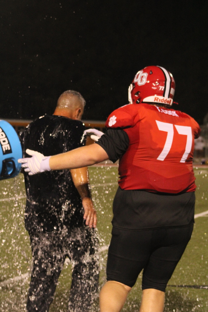 Football players pour water over a coach's head to celebrate his 100th career win.
