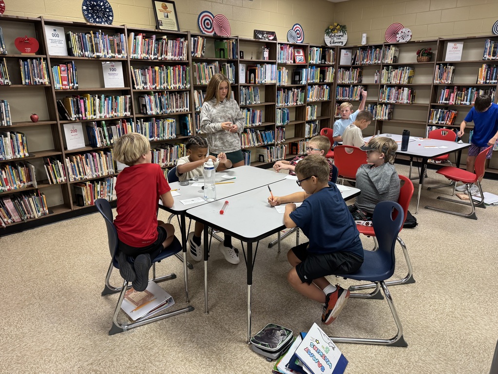 students in a library at a table working on a project